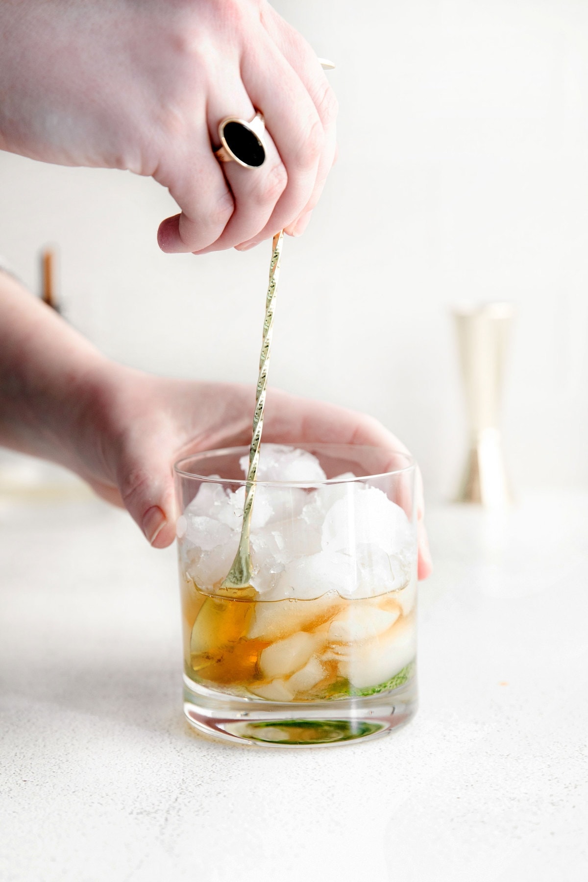 bourbon being stirred into a glass of ice with muddled mint for a mint julep.