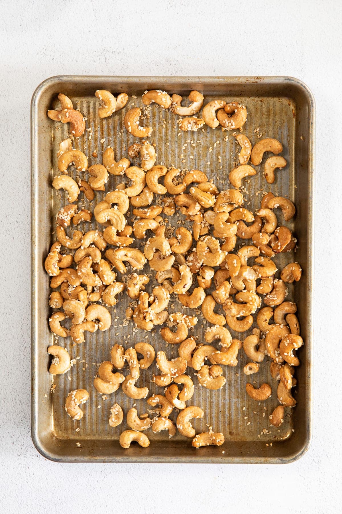 roasted cashews on a pan with sesame seeds