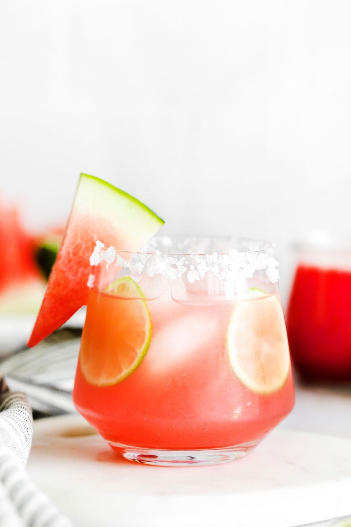 Watermelon margarita served in a glass with a slice of watermelon on the rim. 