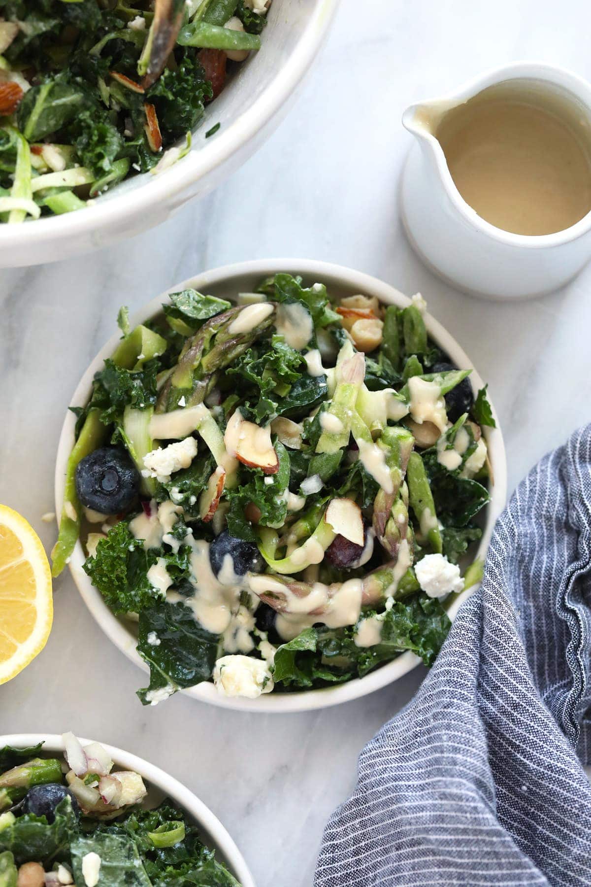 A bowl of asparagus salad and dressing on the side. 