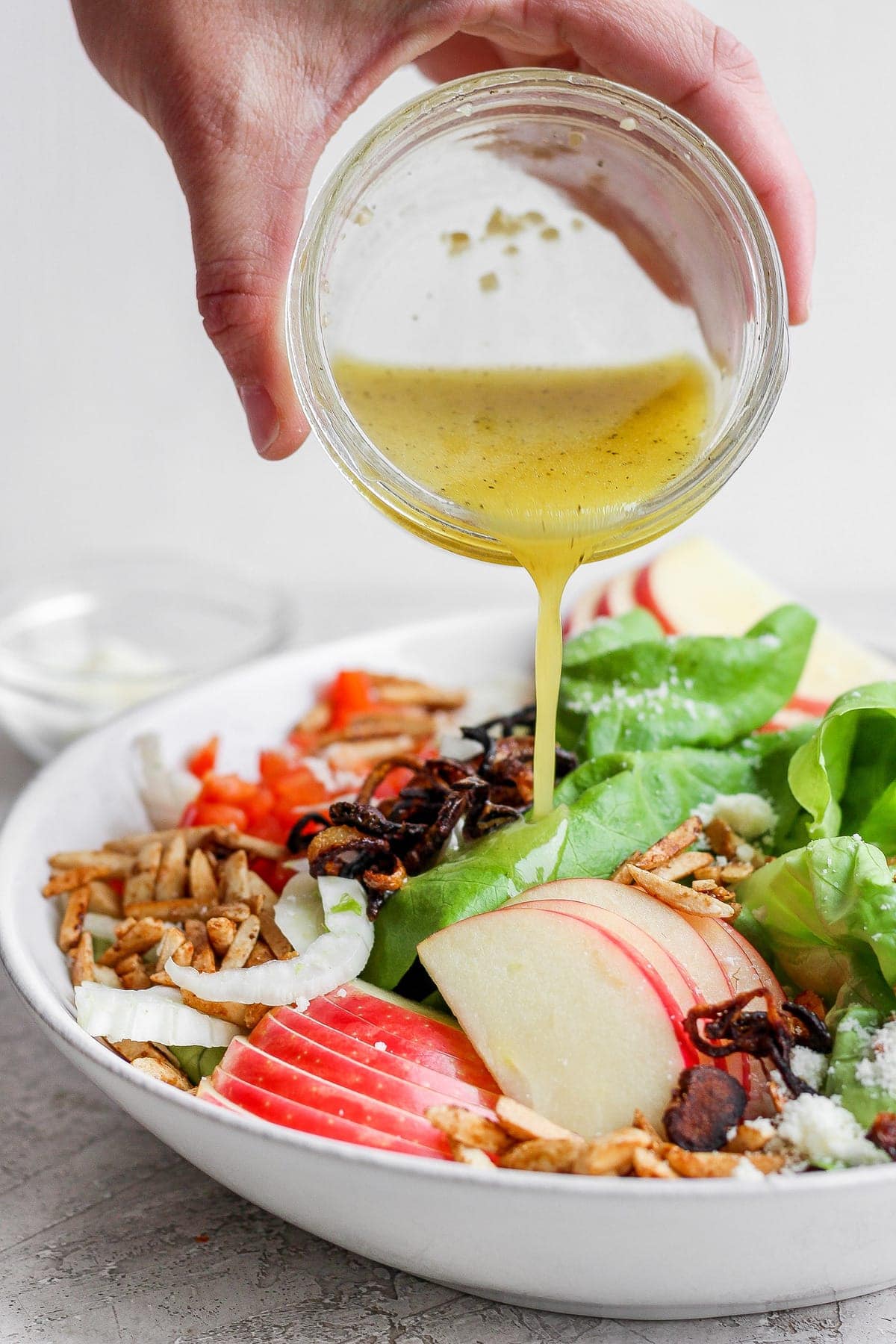 Pouring lemon vinaigrette over the butter lettuce salad