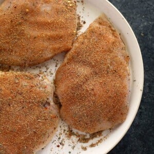 Seasoned chicken breasts on a plate.