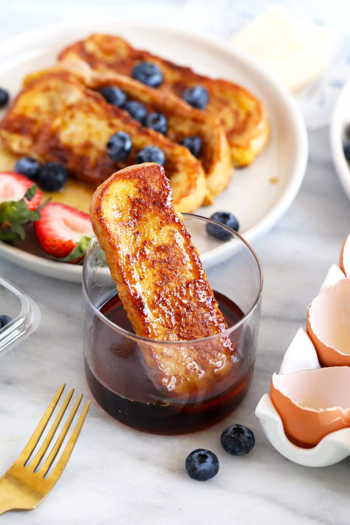 french toast stick in a cup of maple syrup