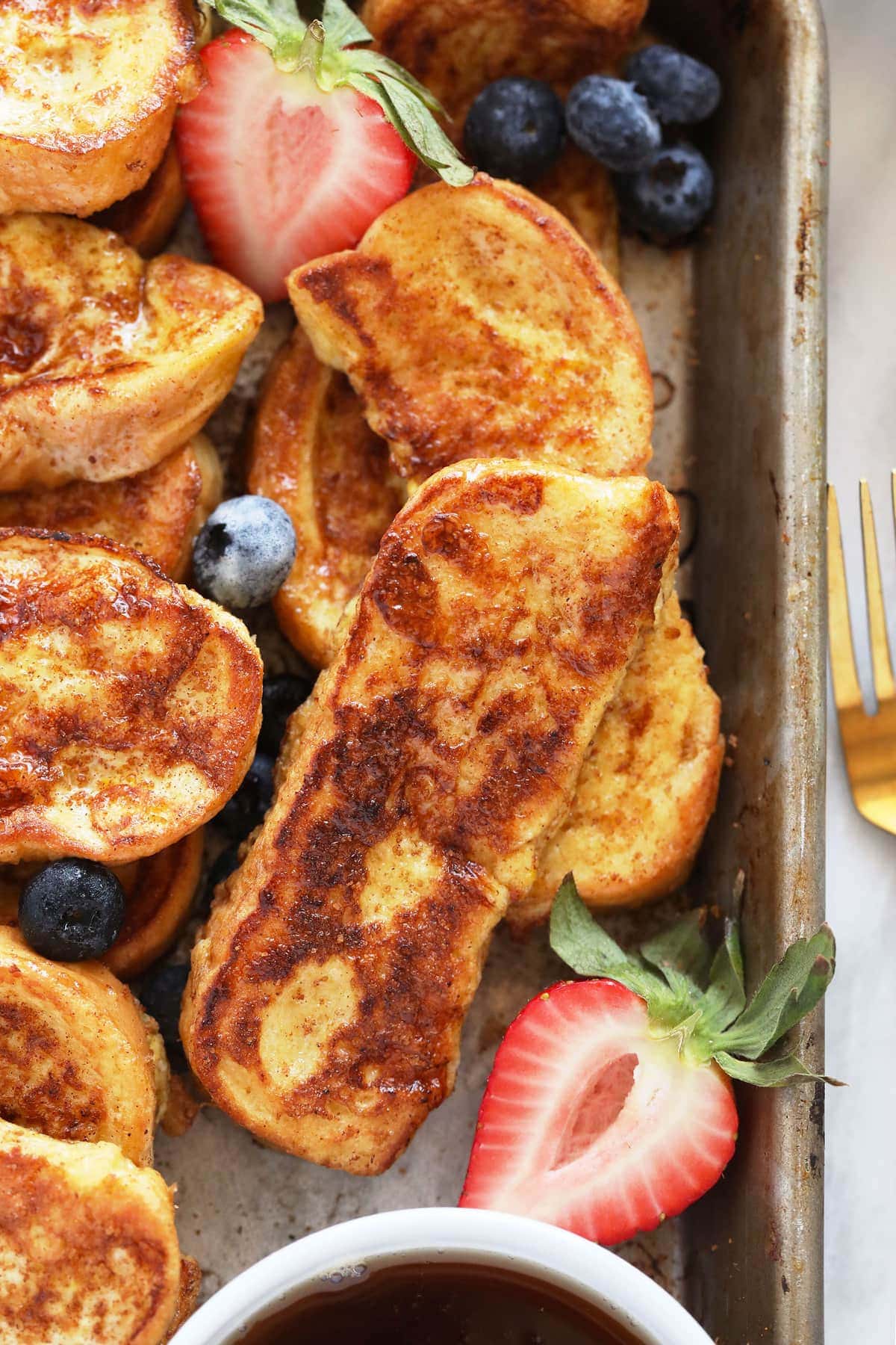 French toast sticks on a baking sheet with strawberries