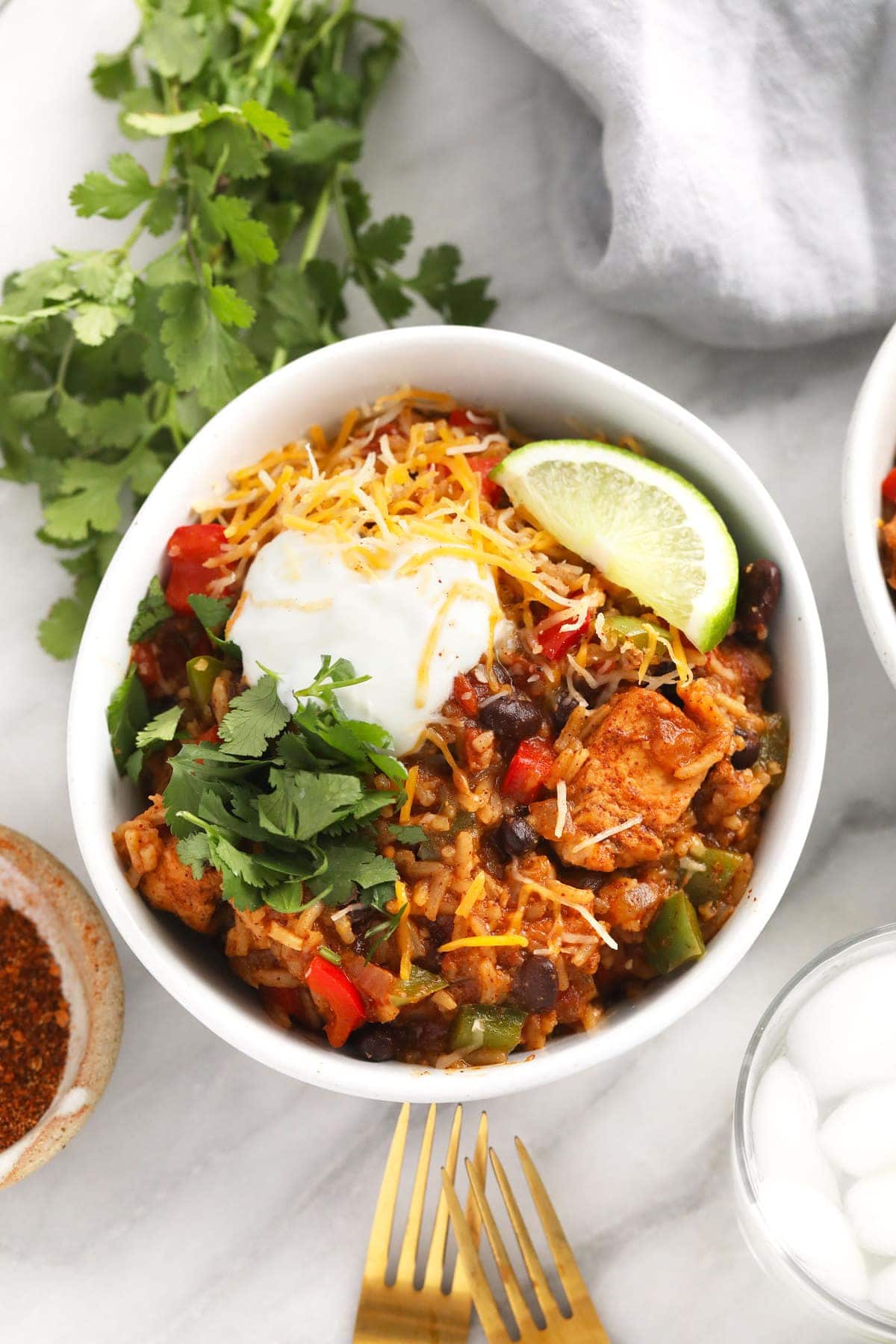 instant pot burrito bowl topped with shredded cheese and greek yogurt and cilantro