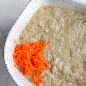 carrot soup in a white bowl with carrots.