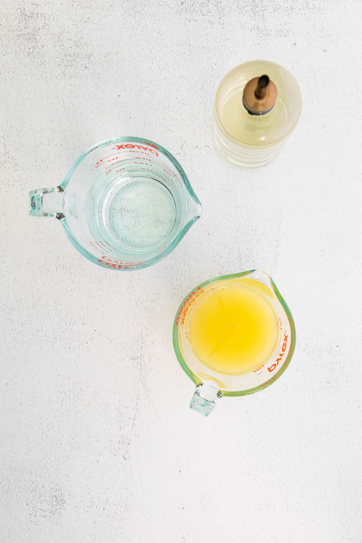 Lemon juice, simple syrup, and water on a counter top. 