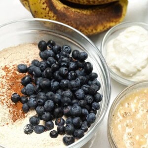 A table topped with bowls of food and bananas, including blueberry banana bread.