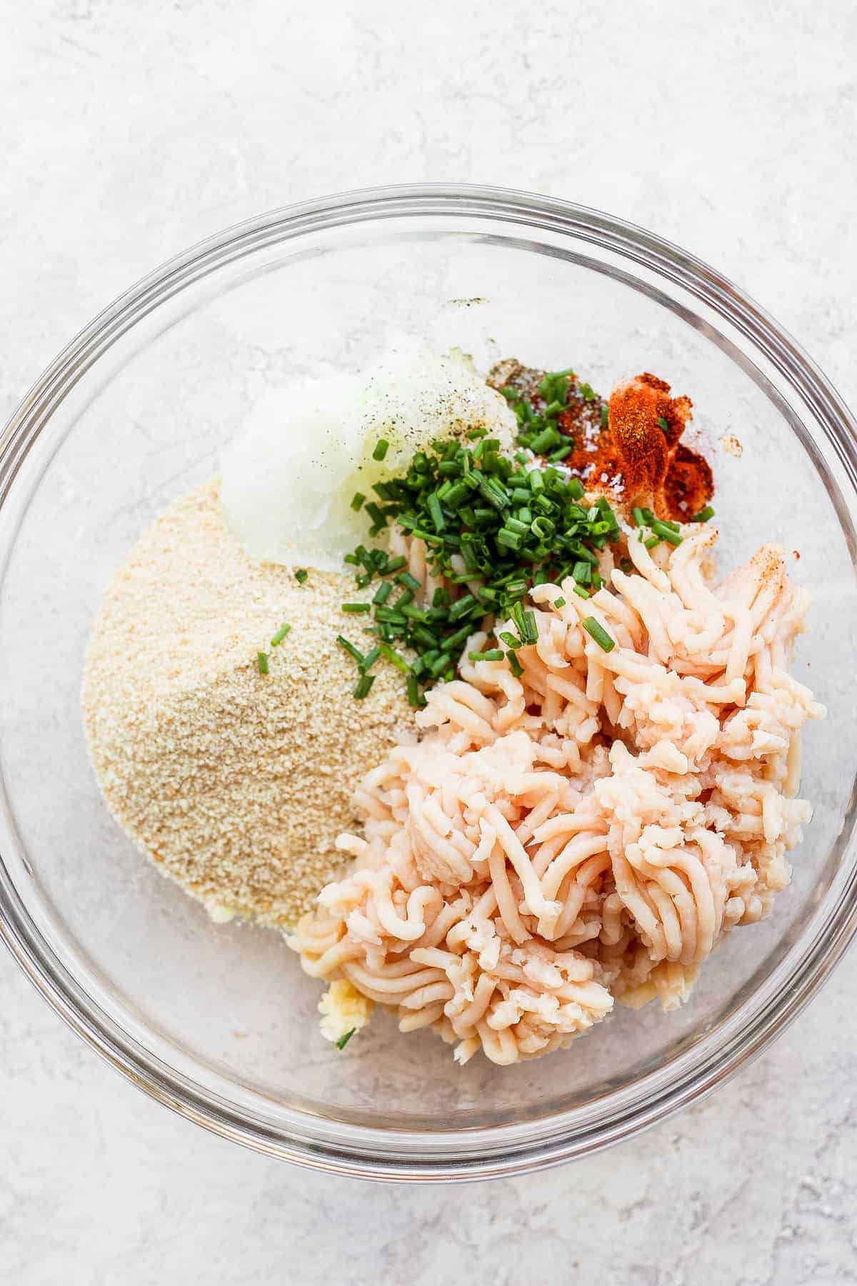 ground chicken, breadcrumbs, onion, and chives in bowl.