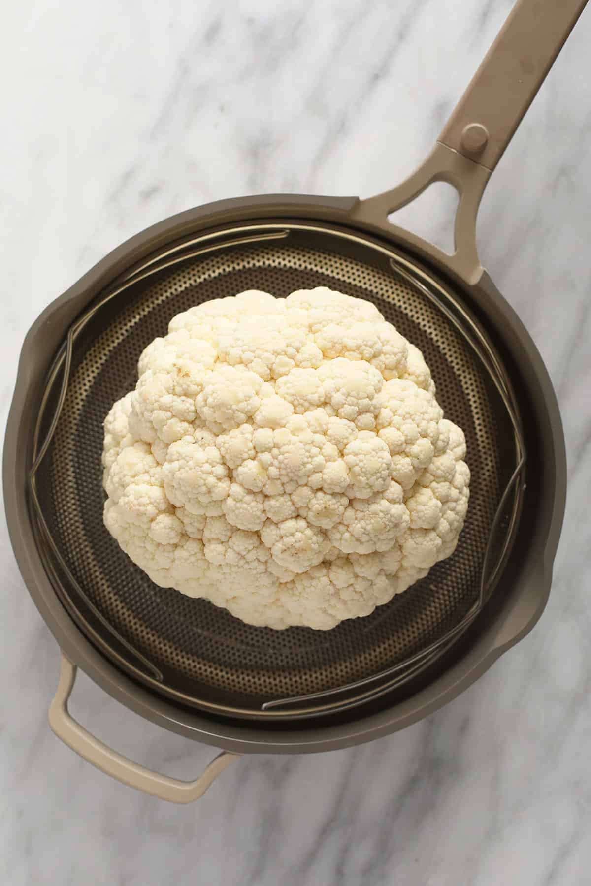 A head of cauliflower in a steamer. 