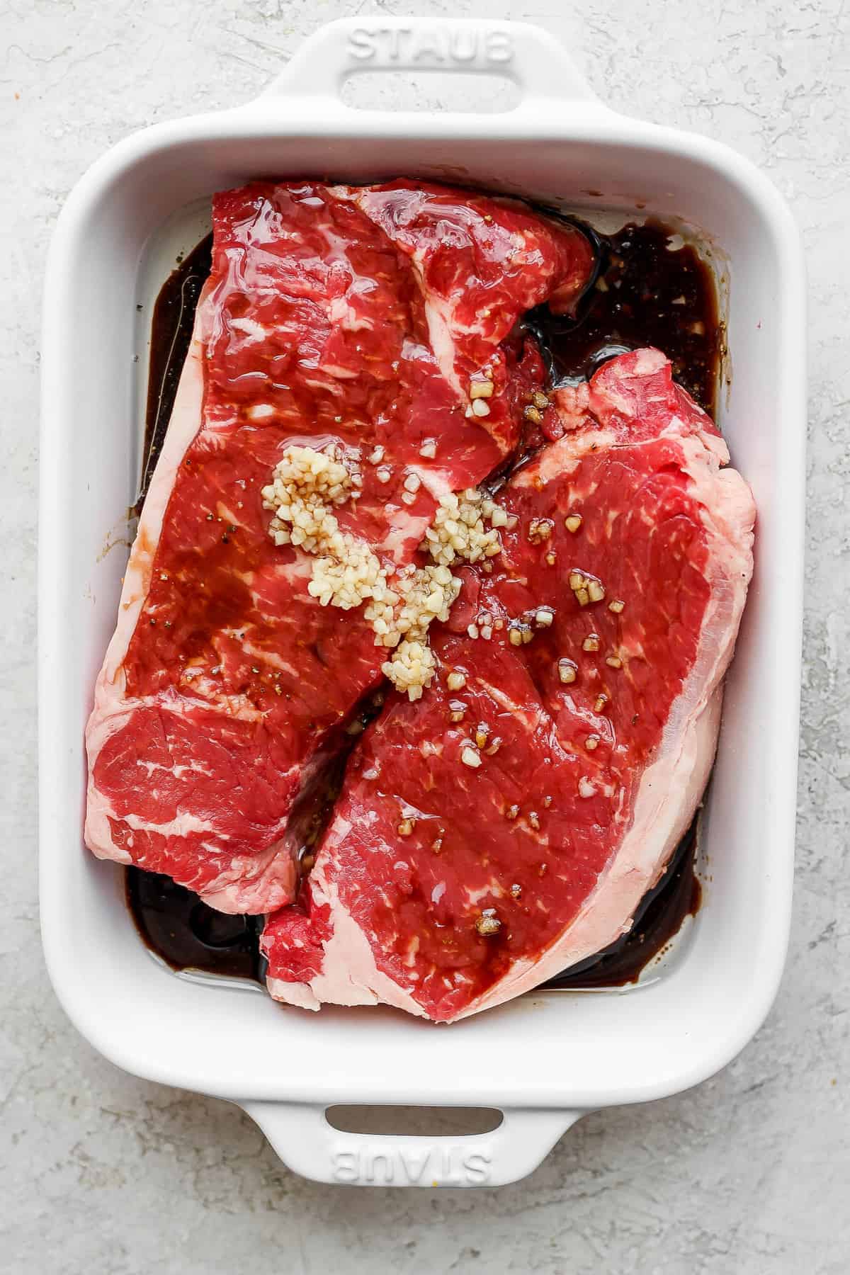 steaks marinating in baking dish.