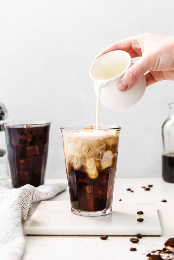 Pouring cream into cold brew coffee