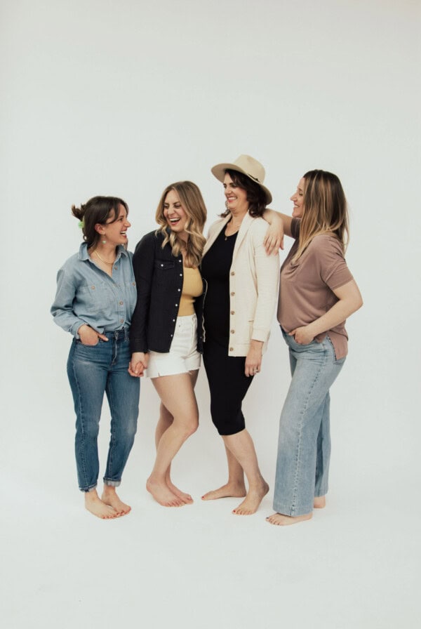 four women posing for a photo in front of a white background.