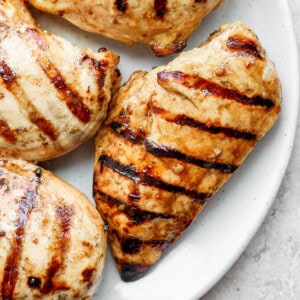 grilled chicken breasts on a white plate.