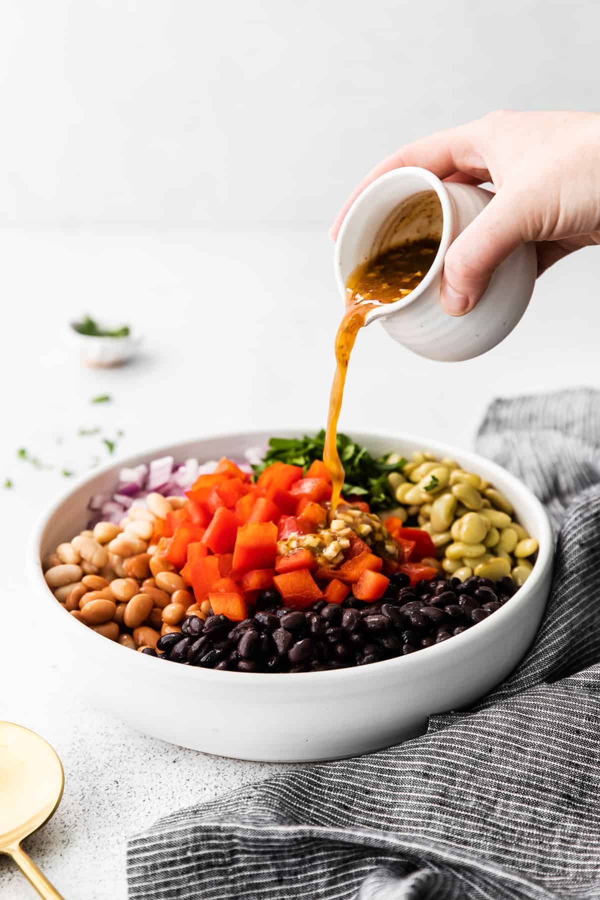 Pouring dressing over the bean dressing. 