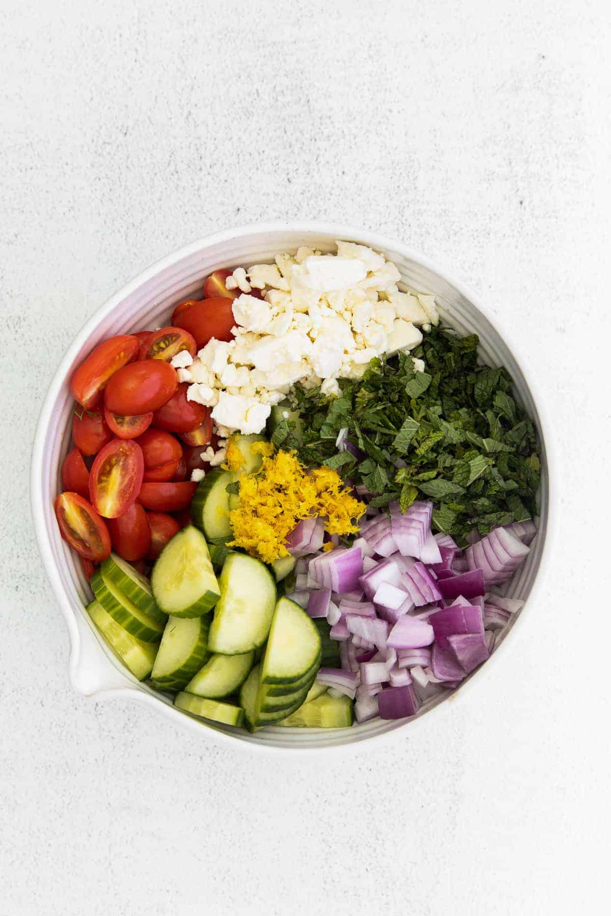 mediterranean cous cous salad ingredients in a bowl