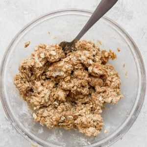 Peach crisp topping sprinkled on oats served in a bowl with a spoon.