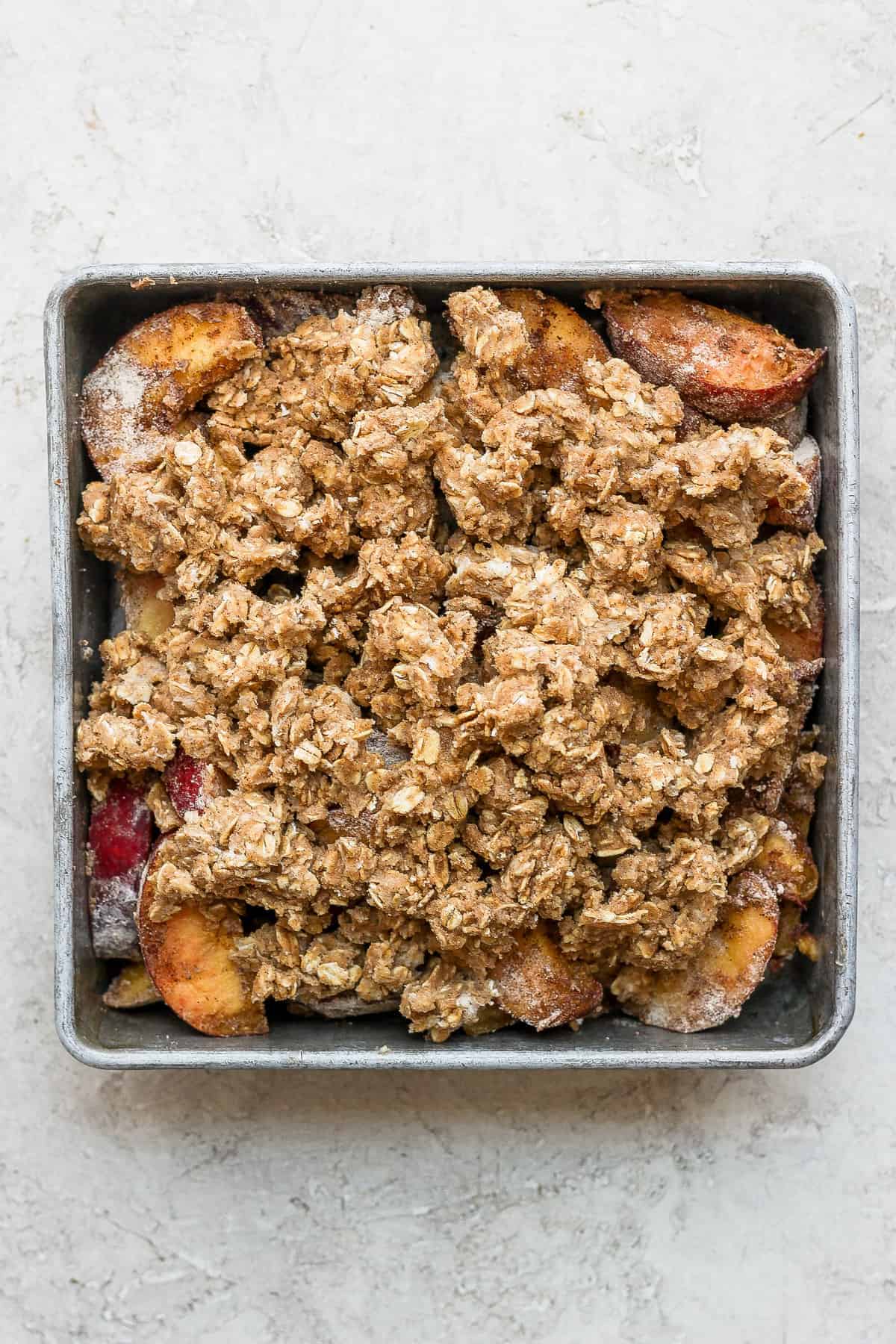 Peach crisp with crumble topping ready to be baked.