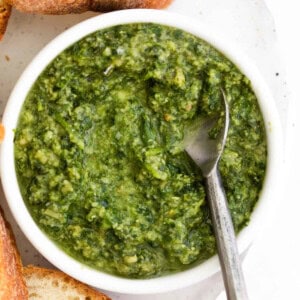 A bowl of homemade pesto with bread and a spoon.