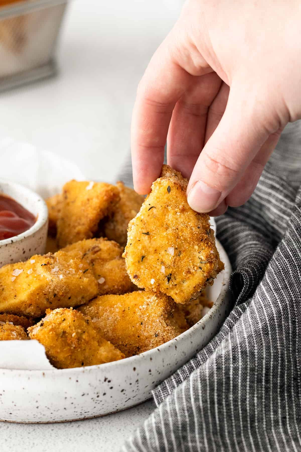 A hand holding an air fryer chicken nugget. 