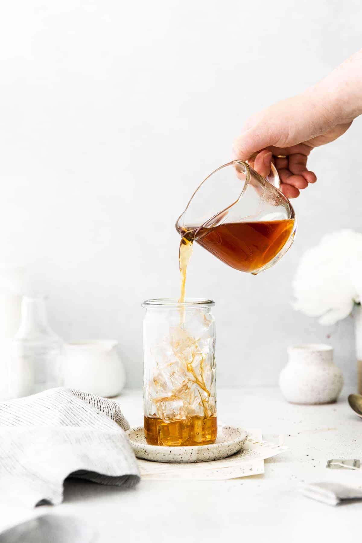 pouring tea into a glass with ice