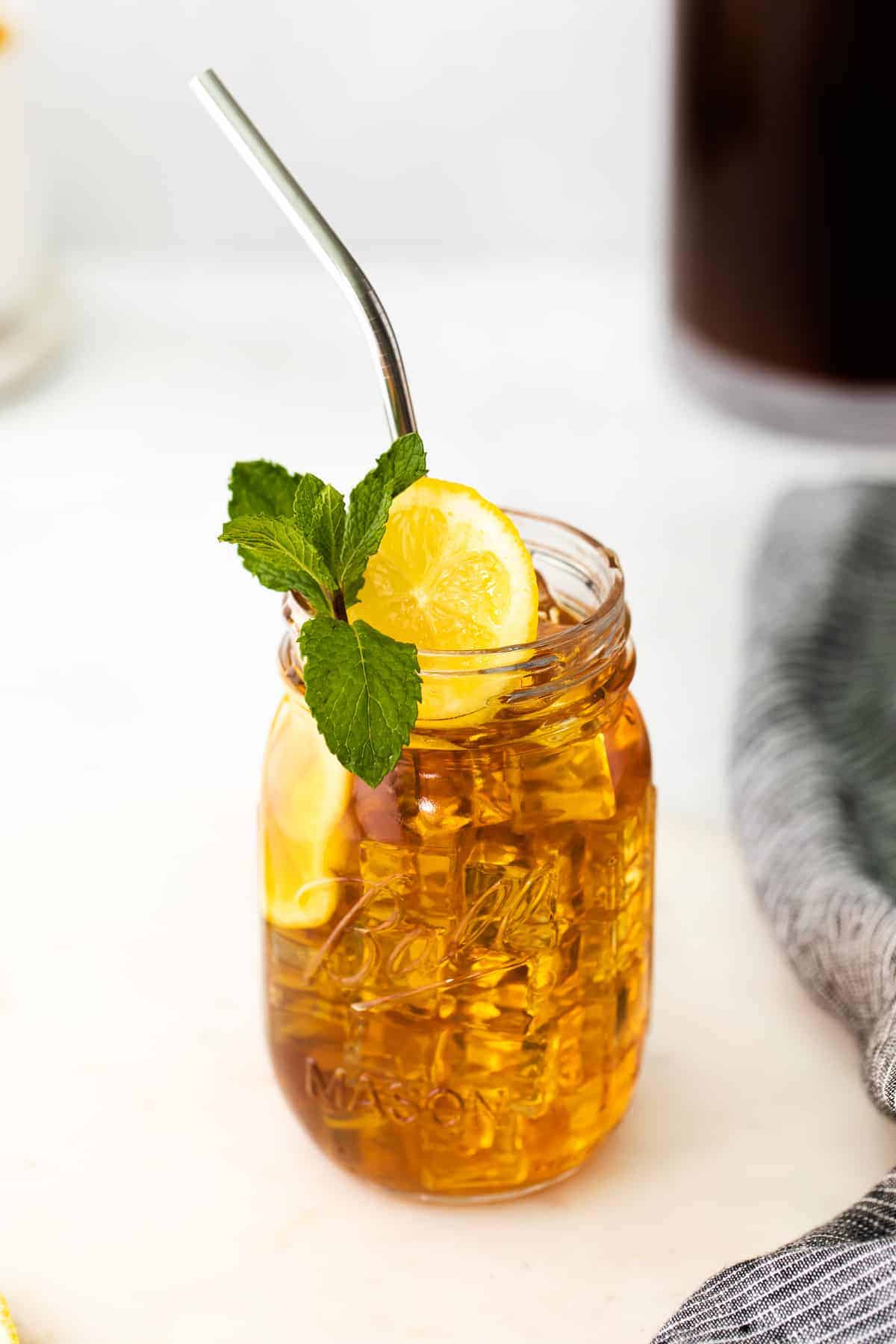 mason jar of iced tea garnished with a slice of fresh lemon and a sprig of fresh mint