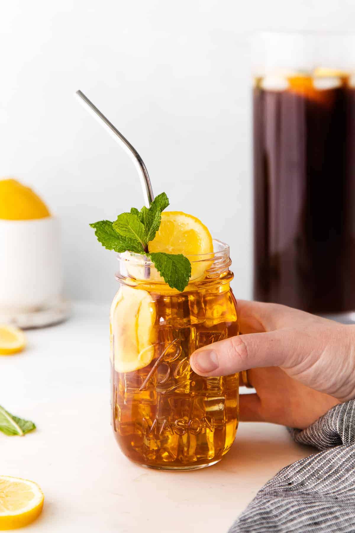 homemade iced tea in a mason jar garnished with mint and a lemon slice