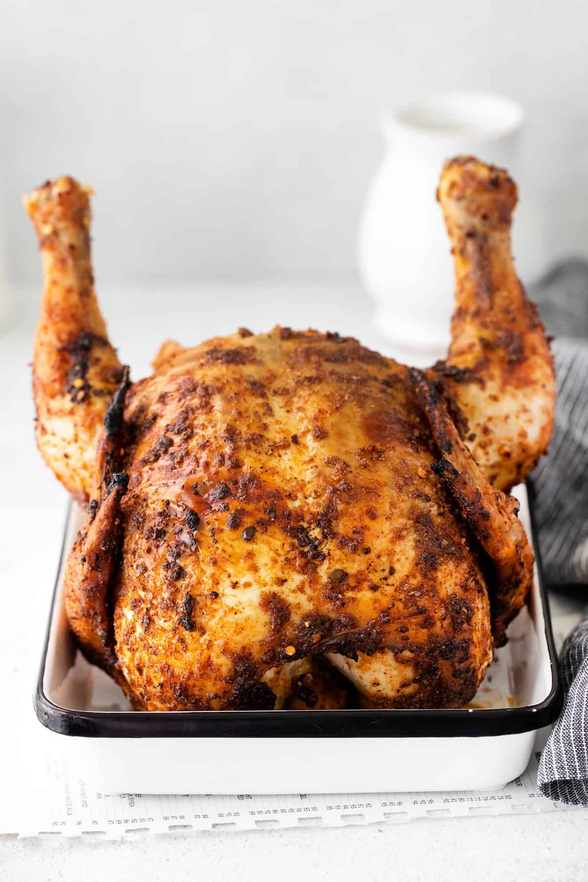 beer can chicken sitting in white pan.