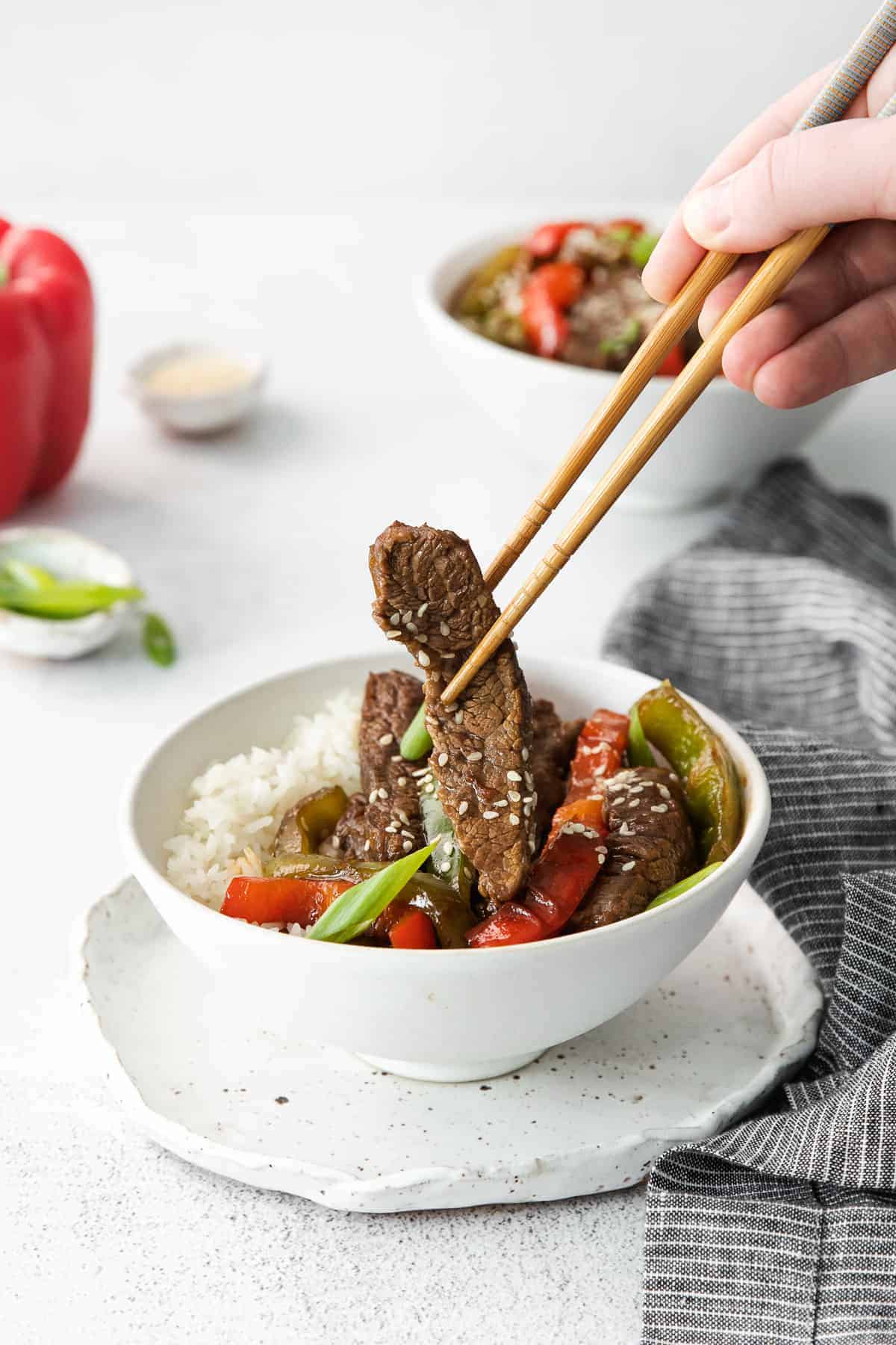 Eating pepper steak with chop sticks.