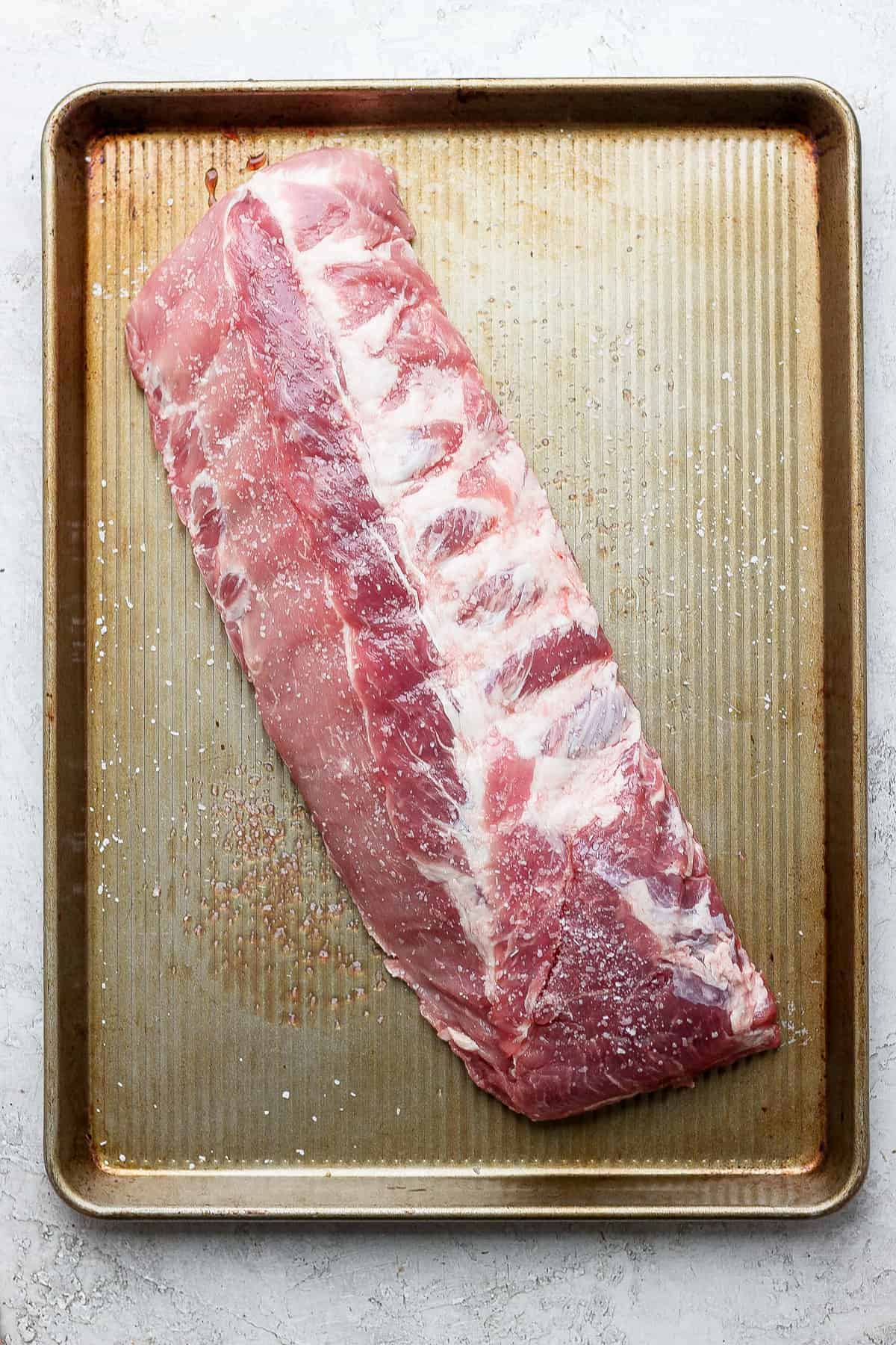 A slab of ribs on a baking sheet. 