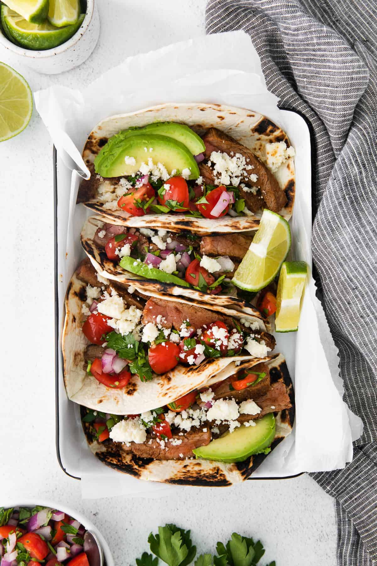 steak tacos topped with sliced avocado and cotija cheese