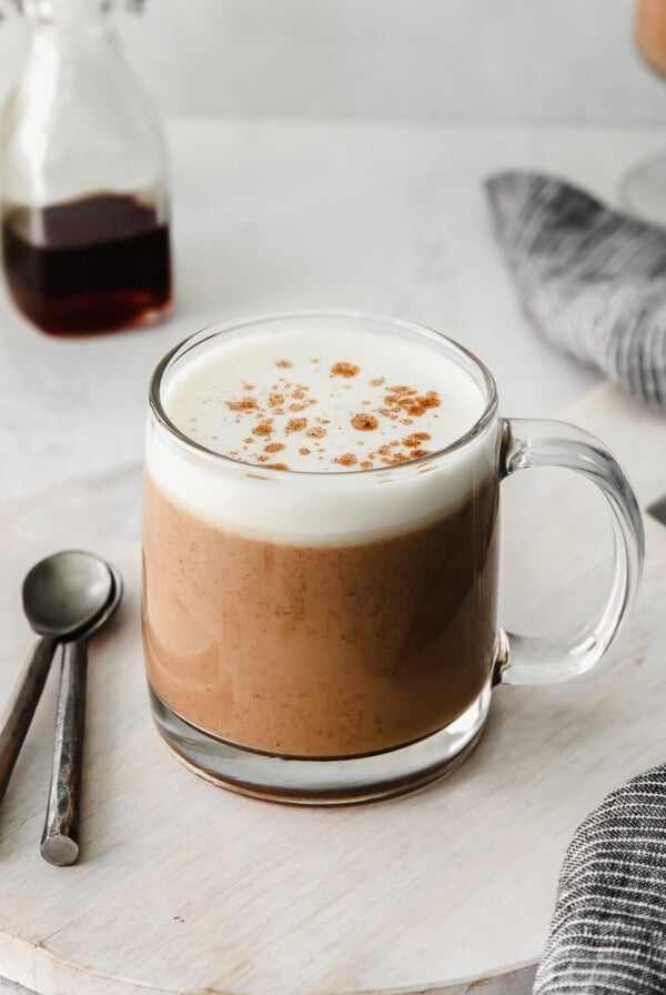 A cup of chai tea latte with whipped cream and cinnamon.