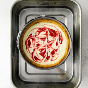 a red and white swirled Greek yogurt cheesecake in a metal pan.