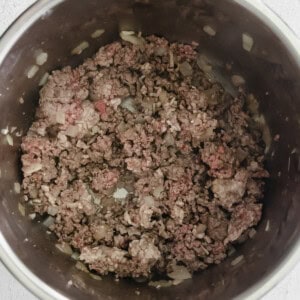 Bowl of instant pot chili with ground beef on a white surface.