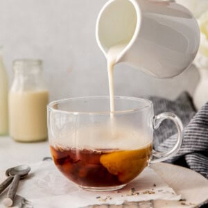 A person pouring milk into a cup of London Fog drink.