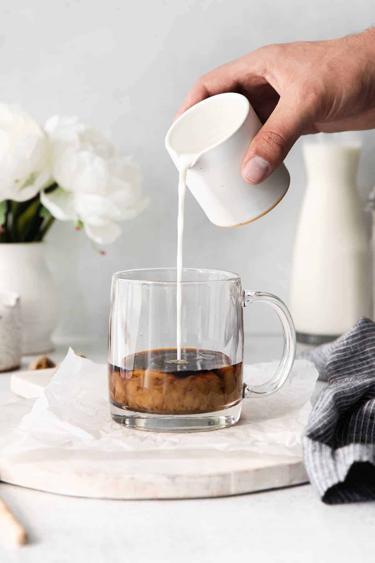 milk being poured into a coffee mug of espresso for a miel