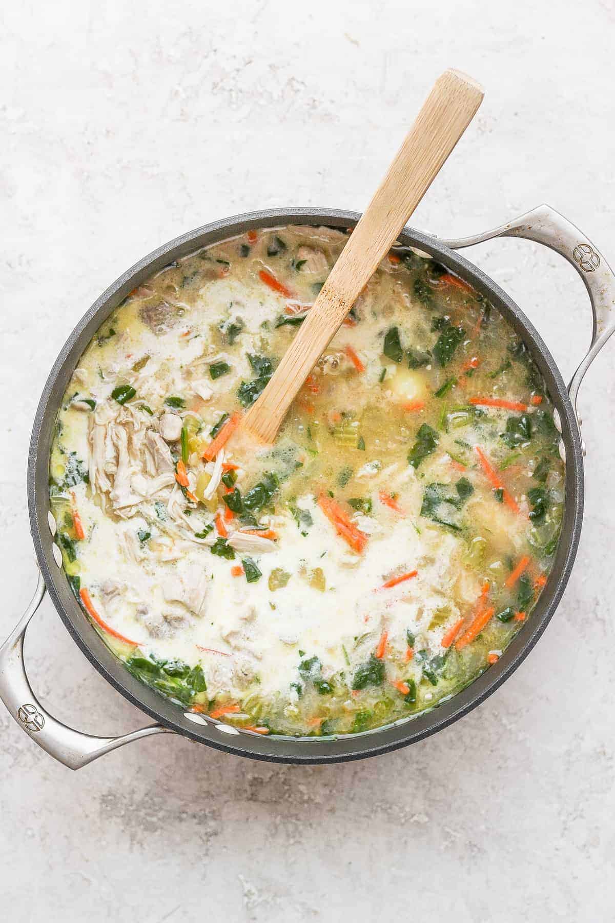 olive garden chicken gnocchi soup with cream being stirred into the soup