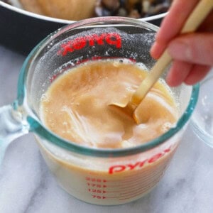 A person pouring a sauce into a measuring cup.