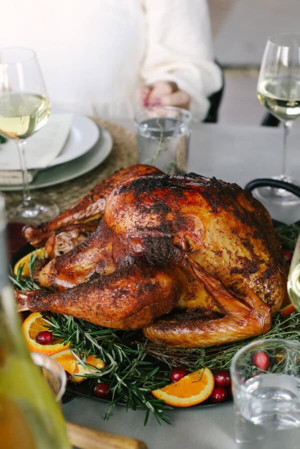 A turkey is sitting on a table with wine glasses.