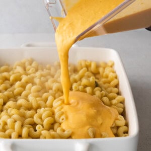 Butternut squash mac and cheese being poured into a baking dish.