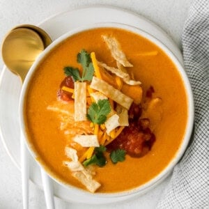 a bowl of mexican chicken soup with tortillas and sour cream.