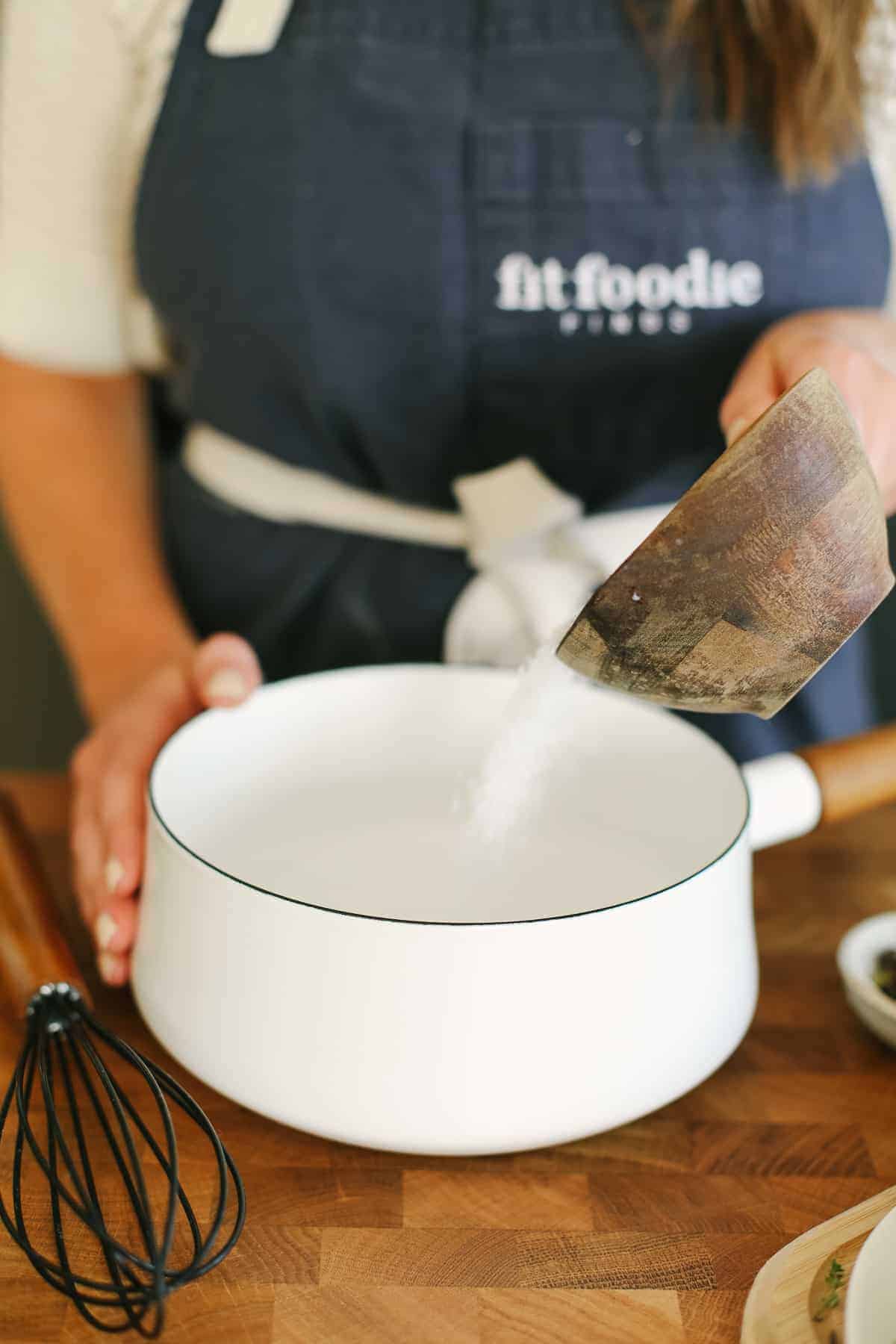 Pouring salt into a small saucepan with water. 