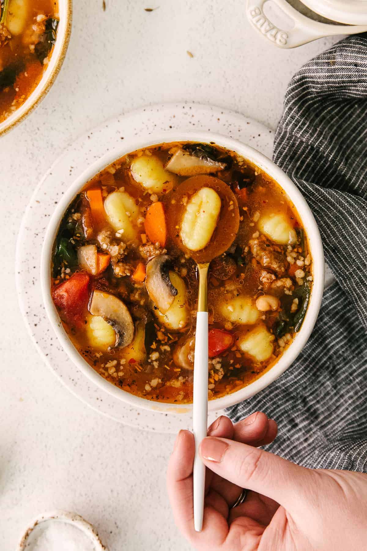 sausage gnocchi soup in a bowl with one gnocchi on a spoon