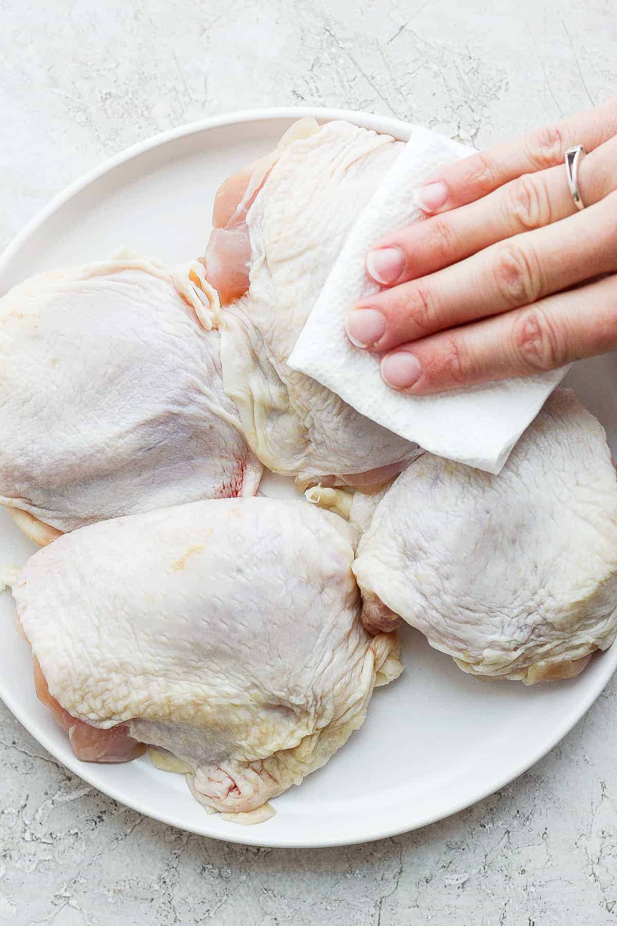 patting chicken thighs with paper towel