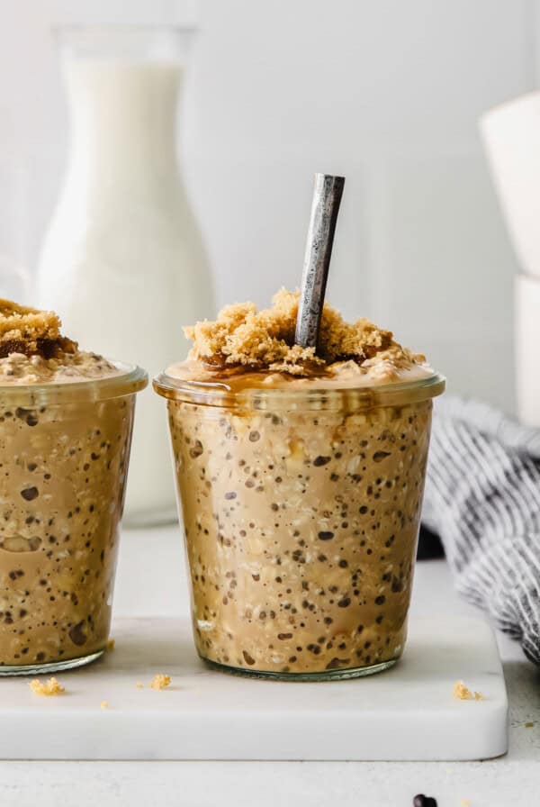 Two jars of oatmeal in front of a glass of milk.