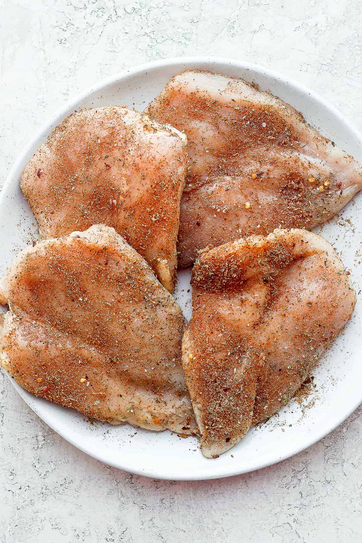 chicken breasts on a plate with a chicken dry rub