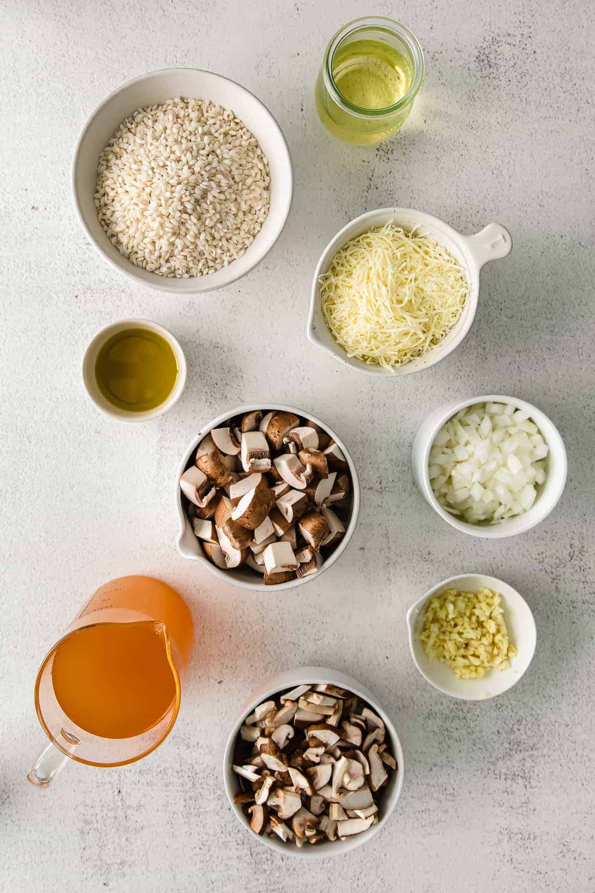 Arborio rice, white onion, parmesan, olive oil, and mushrooms in small bowls. 