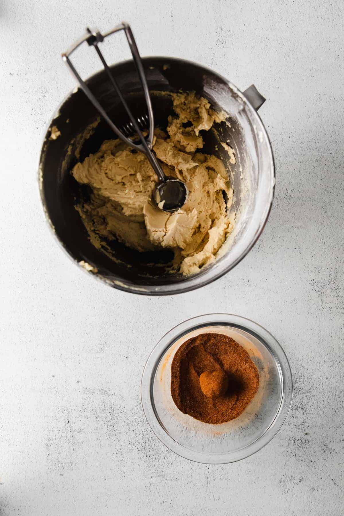 Snickerdoodle cookie dough with a cookie scoop in the bowl. 