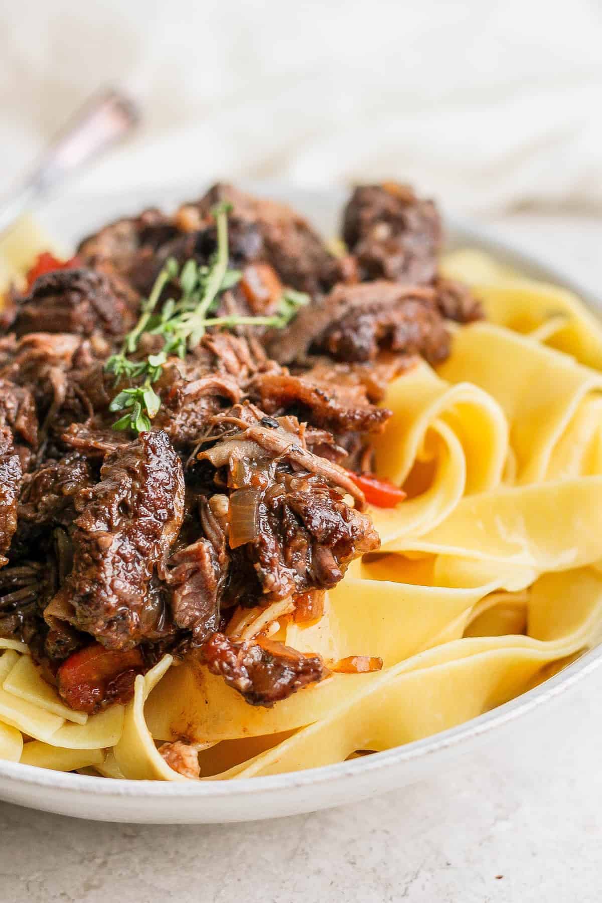 Short rib ragu on a plate with pappardelle noodles.