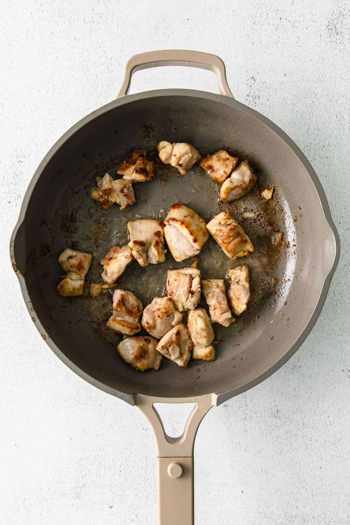 Chicken thighs browning in a skillet pan.